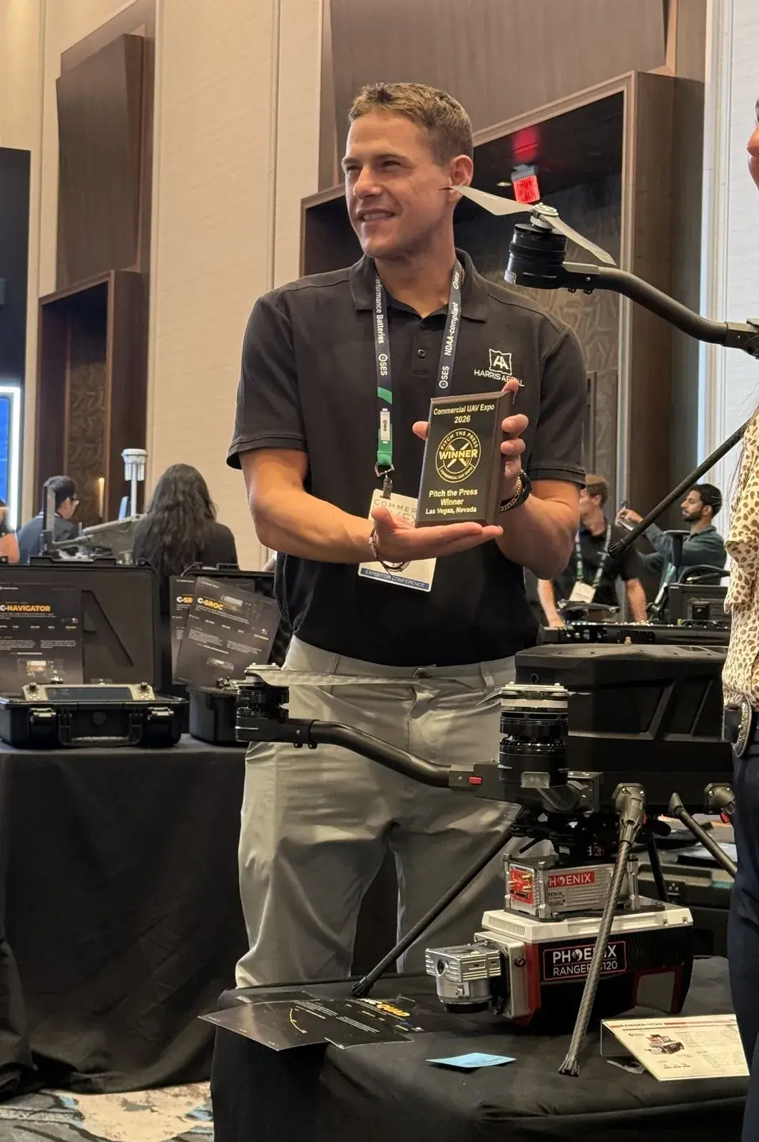 Harris Aerial at Booth 803 during Commercial UAV Expo 2026, holding the Pitch the Press Winner plaque, with a Phoenix LiDAR Ranger U120 on the booth table